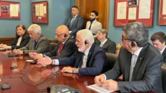 Senadores brasileiros sentados em uma mesa em uma sala de reunião com políticos americanos