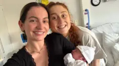 Georgia holding a newborn baby and Daisy 