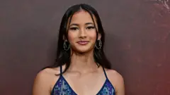 Kaylee Hottle lleva un vestido brillante azul y morado y pendientes de aro plateados.