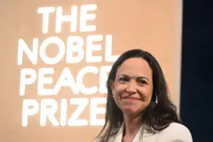 María Corina Machado sonríe, con el cartel del Premio Nobel de la Paz de fondo