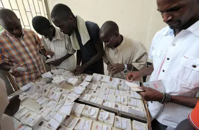 Des hommes s'affairant autour de lots de cartes d'identité