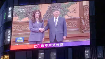 北京某大樓外牆上的大型屏幕在播映中國中央電視台《新聞聯播》，正播報著鄭麗文（左）與習近平（右）在人民大會堂會晤的報導（10/4/2026）