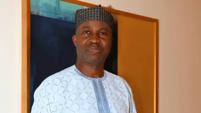 Wale Akorede, Okunnu wọ aṣọ olómi aro, dé fìlà dúdú, ó ń wo ọ̀ọ́kán 