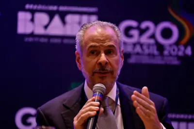 André Corrêa do Lago com microfone na mão em evento do G20 com banner atrás de si 