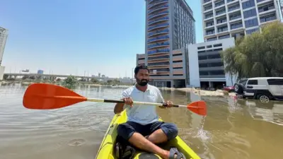 A man in a kayak in floodwater in Dubai