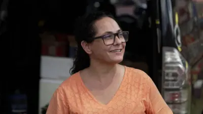 Renata, de camisa laranja, aparece de perfil sorrindo