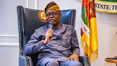 Aworan gomina ṣeyi makinde lori ijoko, o si fi ọwọ ọtun gbe ẹrọ gbohungbohun si ẹnu.