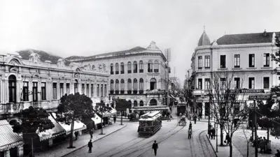 Foto em preto e branco do Largo de São Bento em 1910, com prédios antigos e um bonde passando.