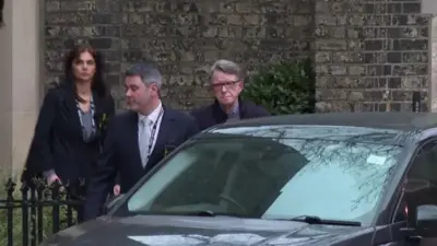 Peter Mandelson, mężczyzna i kobieta widoczni są za ciemnym samochodem