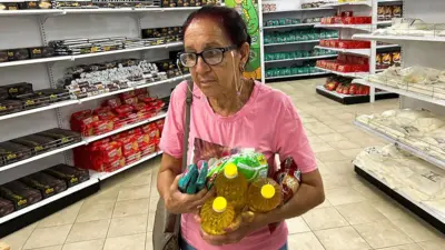 Mujer sostiene varios productos en un supermercado estatal dolarizado en un barrio de La Habana. 