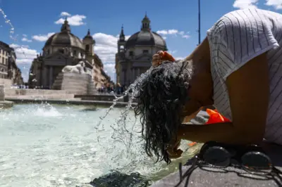 Roma'da sıcak hava dalgası sırasında bir havuzda yüzünü yıkayarak serinlemeye çalışan bir kadın, 28 Haziran 2025.