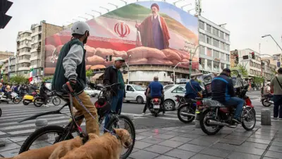 Motorists pass under a banner featuring a portrait of Mojtaba Khamenei, Iran's new Supreme Leader, on a busy street in Tehran