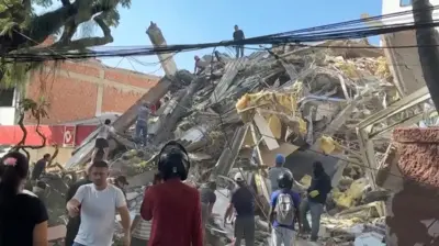 Rescue workers and residents stand around collapsed building for di aftermath of earthquake for Cali, Colombia, August 10, 2026.