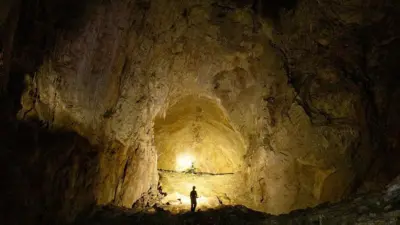 Человек стоит внутри пещеры.