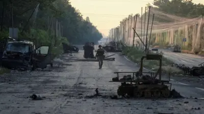 Український військовий на дорозі серед спаленої техніки