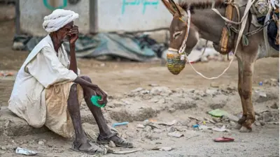 Un vieil homme attend de remplir sa citerne tirée par un âne lors d'une crise de l'eau à Port-Soudan, dans un Soudan déchiré par la guerre, le 9 avril 2024. 