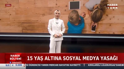 تصویر یک شبکه تلویزیونی، یک مجری محجبه با لباس سفید، پشت سر او، نمایی از بالای دو کودک در حال بازی دیده می‌شود