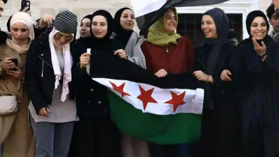8 Kasım'daki yönetim değişikliğinin ardından İstanbul Fatih'teki kutlamalara katılan Suriyeli kadın bayrak taşıyor