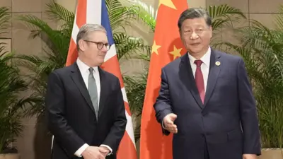 身穿西服的施紀賢爵士(左)與習近平(右)在巴西里約熱內盧G20峰會週邊會晤,兩人站在英國與中國國旗前合照(18/11/2024)