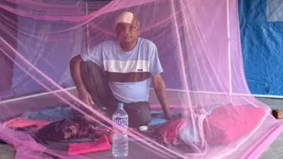 सुकुम्बासी बस्तीबाट विस्थापित भएपछि होल्डिङ सेन्टरमा भुइँमा राखेको ओछ्यानमा बसेका एक व्यक्ति