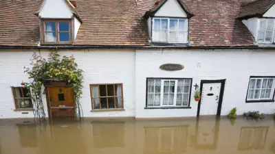 A row of pretty old white cottages in the centre of Tewkesbury in Gloucestershire has been inundated with brown floodwater, which is almost up to the bottom of the ground floor windows. 