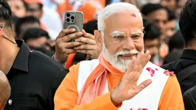 Narendra Modi wears orange garments while he waves to the crowd during his roadshow on the eve of filing of his election nomination papers, in Varanasi on May 13, 2024.