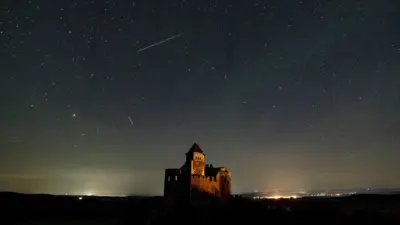 A castle and the night sky showing stars and a meteor