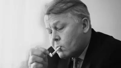 Александр Твардовский в костюме и галстуке закуривает сигарету