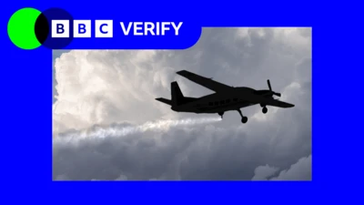 تصویر سایه‌نمای یک هواپیمای کوچک در حال پاشیدن ذرات کوچک به آسمان دیده می‌شود که یک دنباله سفید بلند در پشت آن تشکیل می‌دهند. هواپیما در پس‌زمینه‌ای از ابرهای سنگین و خاکستری پرواز می‌کند. لوگوی بی‌بی‌سی وریفای در گوشه بالا سمت چپ دیده می‌شود.