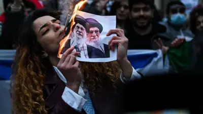 زنی معترض در حال سوزاندن عکس خامنه‌ای