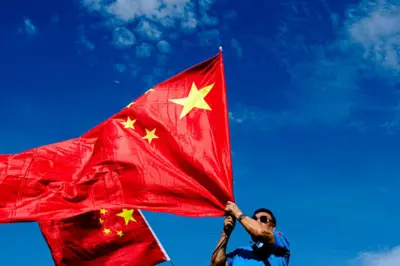 2024年10月1日，一名男子在香港的国庆庆典上挥舞中国国旗。为纪念中华人民共和国成立75周年，全国各地举行庆祝活动。