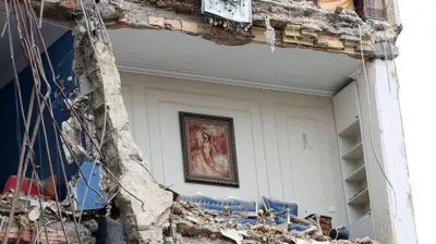 نمایی از اتاقی که یک طرفش فروریخته و در میان خرابه ساختمانی است