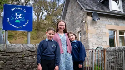 Pupils Molly and Shannon stand in their uniforms outside the building of Duror Primary School