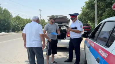ЖКККББнын өкүлү таксисттин лицензиясын текшерип жатат