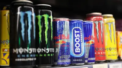Close of of differnet energy drink brands lined up on a shelf in a supermarket