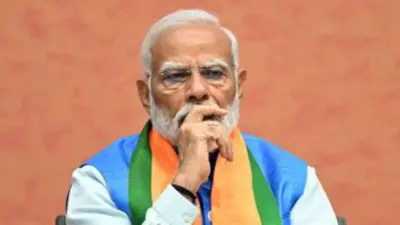 Narendra Modi looks thoughtful sitting at a table covered in flowers