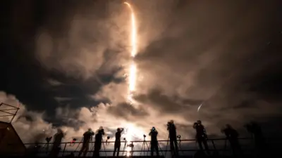 photographers silhouetted against rocket take off