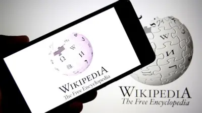 Na tej ilustracji fotograficznej widoczne jest logo Wikipedii wyświetlane na smartfonie w tle