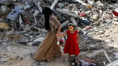 パレスチナ自治区ガザ地区のがれきの中を歩く母娘