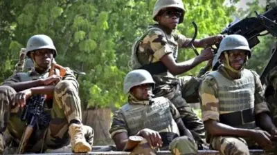 Awọn ọmọ ologun to wa ninu asọ khaki wọn de ate sori, wọ ẹwu ayẹta, wọn si gbe ibọn lọwọ, gbogbo wọn joko sori ọkọ ijagun