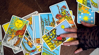 Карты таро раскладывает на столе женская рука