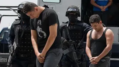 Miembros de La Familia Michoacana esposados son escoltados por las fuerzas de seguridad de México