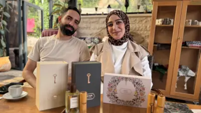 Qassem Abu Khalaf and his wife Malak Hijaz with a range of their perfumes on a wooden table.