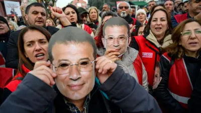 Fotoğrafta, 31 Ocak 2025'te yapılan bir gösteride İmamoğlu'nun maskelerini taşıyan göstericiler görülüyor. Bazıları da slogan atıyor. 