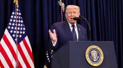 紺の幕と星条旗などを背に、大統領印のついた演台を前にマイクに向かって話す紺色スーツ姿のトランプ氏