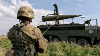 Военный смотрит за погрузкой ракеты комплекса "Искандер-М"