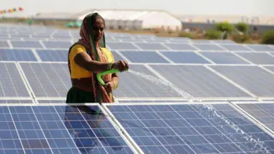 सौर पैनल को पानी से साफ़ करती एक महिला