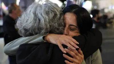 Two women embrace at a public demonstration after ceasefire and hostage deal was agreed