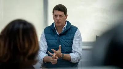 Ricardo Salles vestindo uma camisa azul listrada sob um colete azul. 