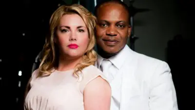 Charmain and Eric - Woman wey light dress and man wear white suit dem pose togeda for one studio-style portrait.